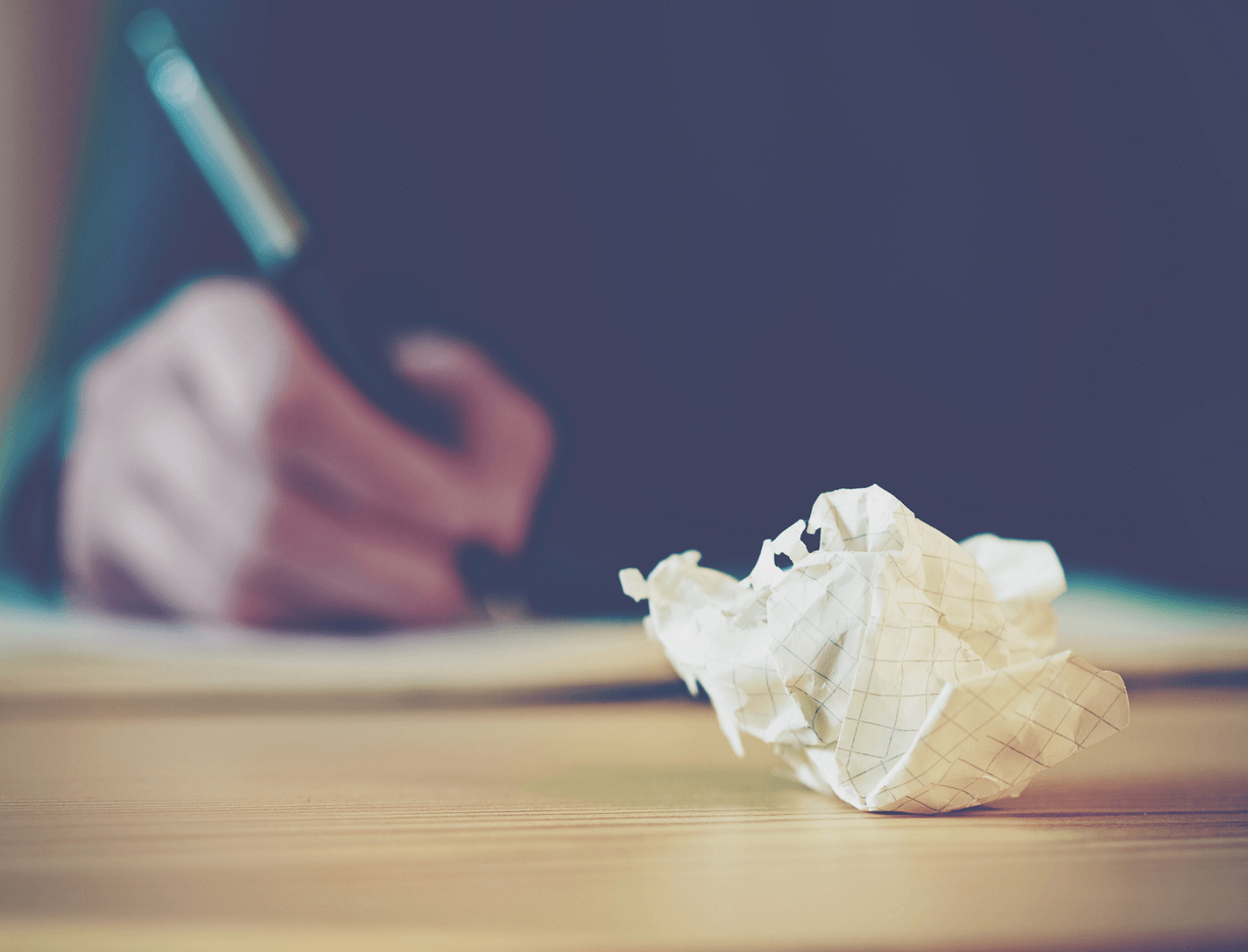 person-writing-next-to-crumpled-paper