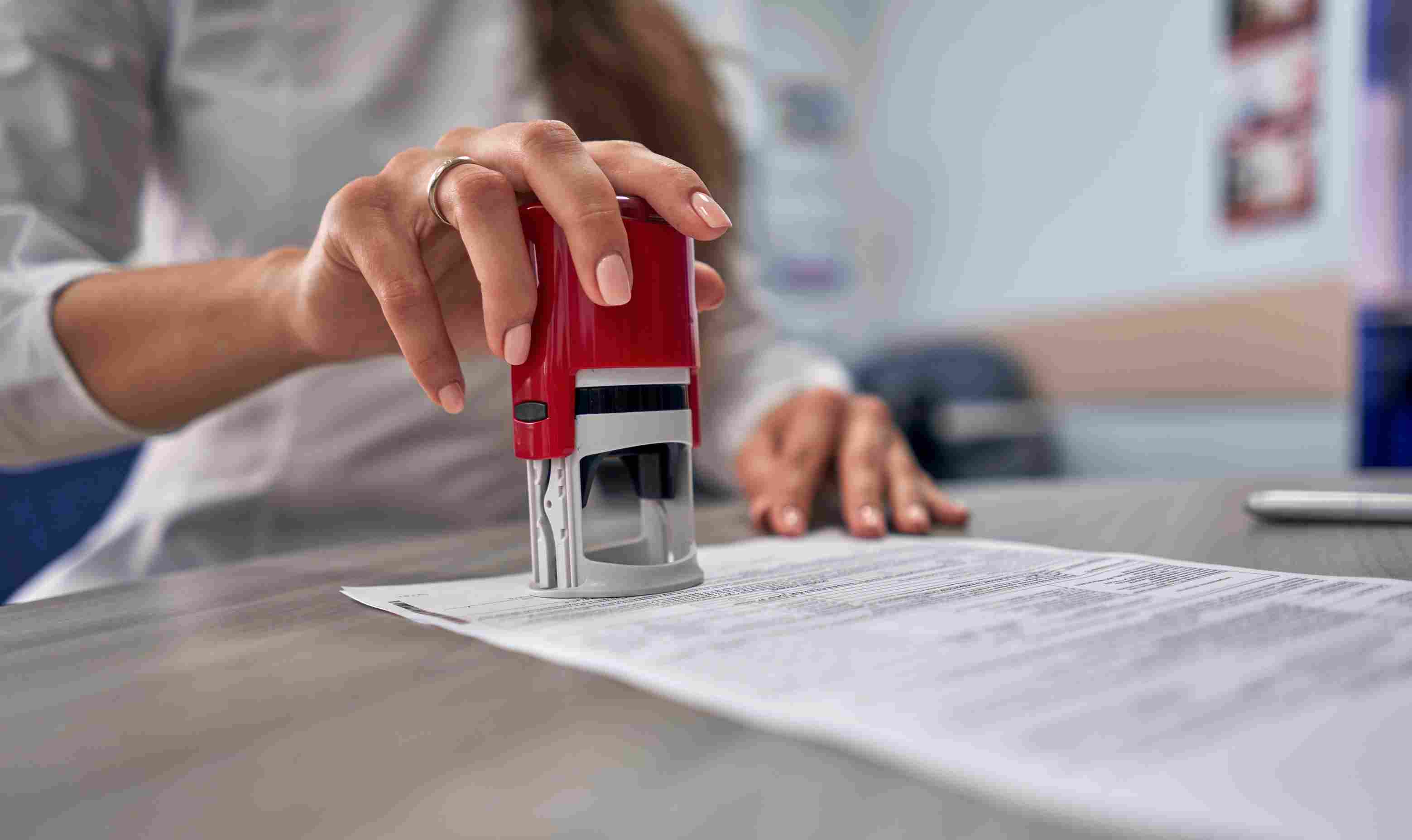 Notary public using a stamp to provide a seal for a document.