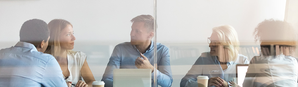 Two men and three women having a meeting in a boardroom.