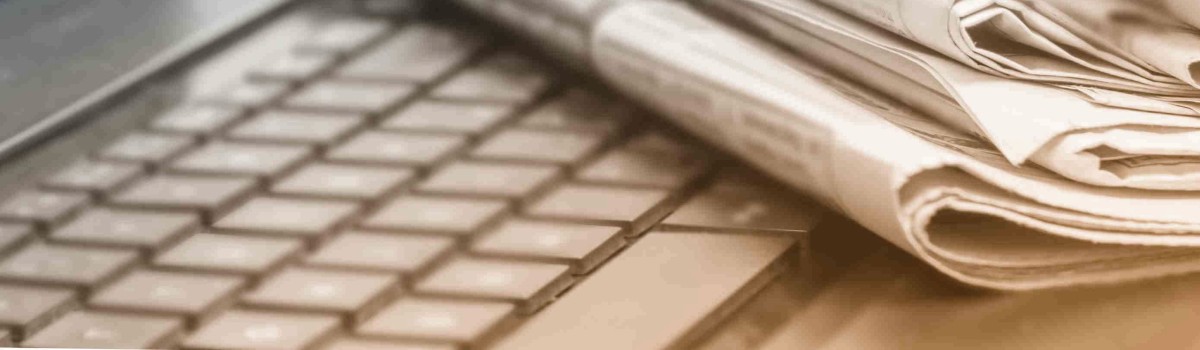 Close-up of a stack of newspapers on top of a computer keyboard. 