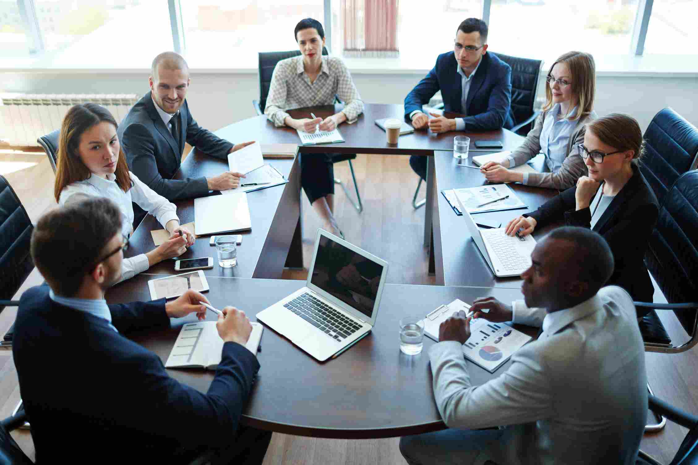 Corporate employees sitting around a boardroom table.